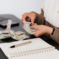 crop payroll clerk counting money while sitting at table